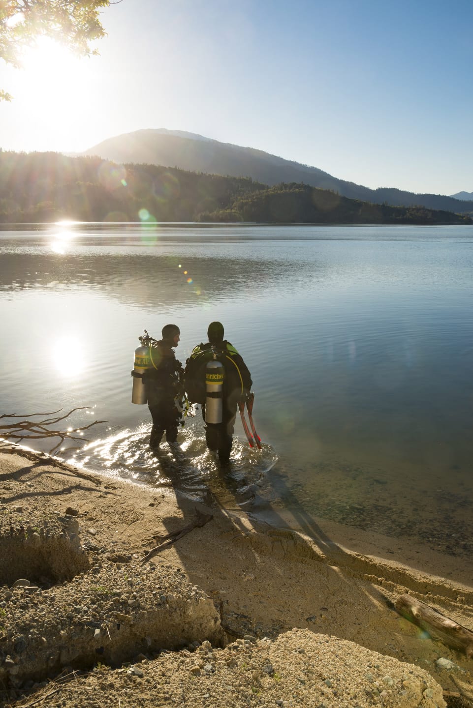 Divers walking along the shoreline with nitrox tanks